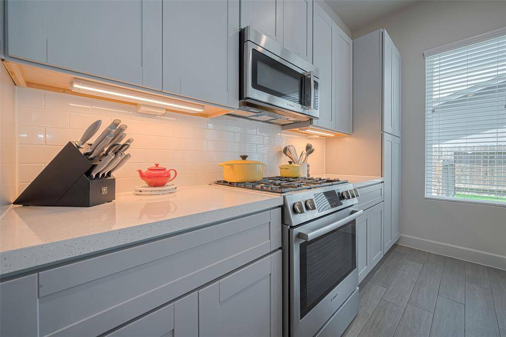 A chef’s dream—this streamlined layout features quartz counters, under-cabinet lighting, a 5-burner gas range, and ample cabinetry for stylish storage and effortless cooking.