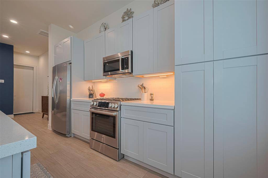 Clean lines and contemporary cabinetry frame this well-equipped kitchen, featuring stainless steel appliances, under-cabinet lighting, and an abundance of storage—designed for style and everyday ease.