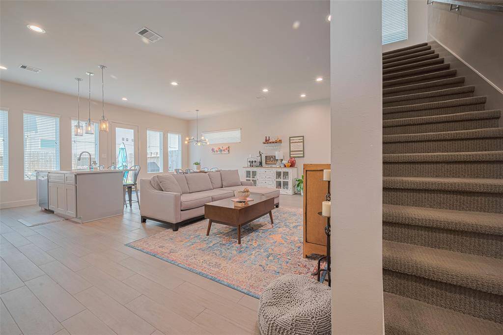 Effortless flow from living to kitchen to upstairs—this open-concept main level is anchored by clean sightlines, natural light, and a tucked-away staircase leading to the private retreat above.