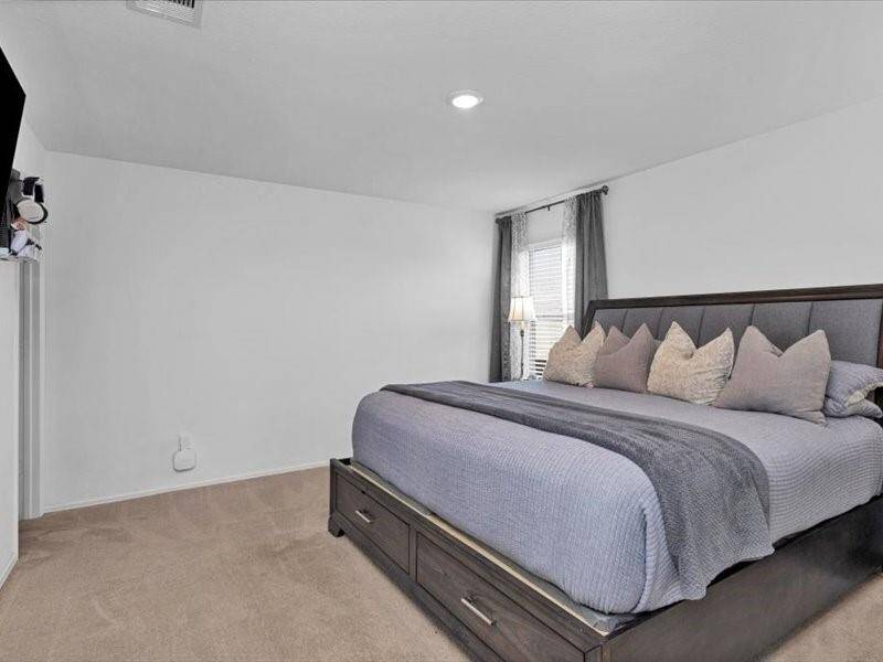 The primary bedroom is a peaceful retreat, featuring a large window that lets in natural light and lush carpeting for a cozy, comfortable feel.
