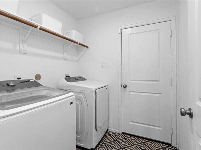The spacious laundry room offers ample storage and a handy rack to hang clothes, keeping everything organized and easily accessible.