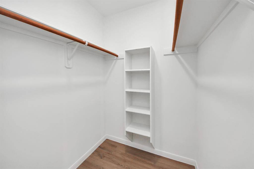 The primary walk-in closet offers generous storage with dual hanging rods and built-in shelving, perfectly designed to keep everything organized and within reach.