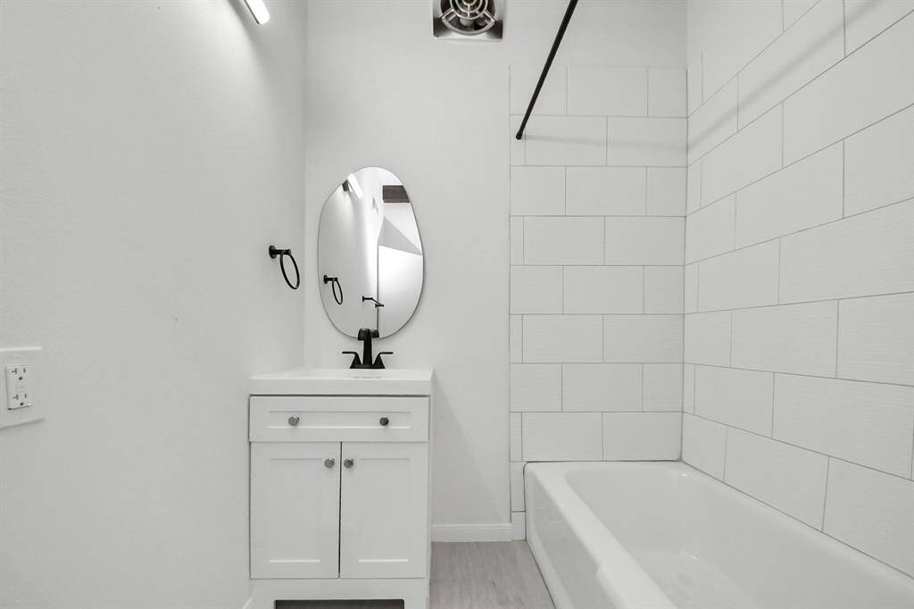 This refreshed secondary bathroom features clean modern lines with crisp white tile, a sleek vanity, and matte black fixtures.