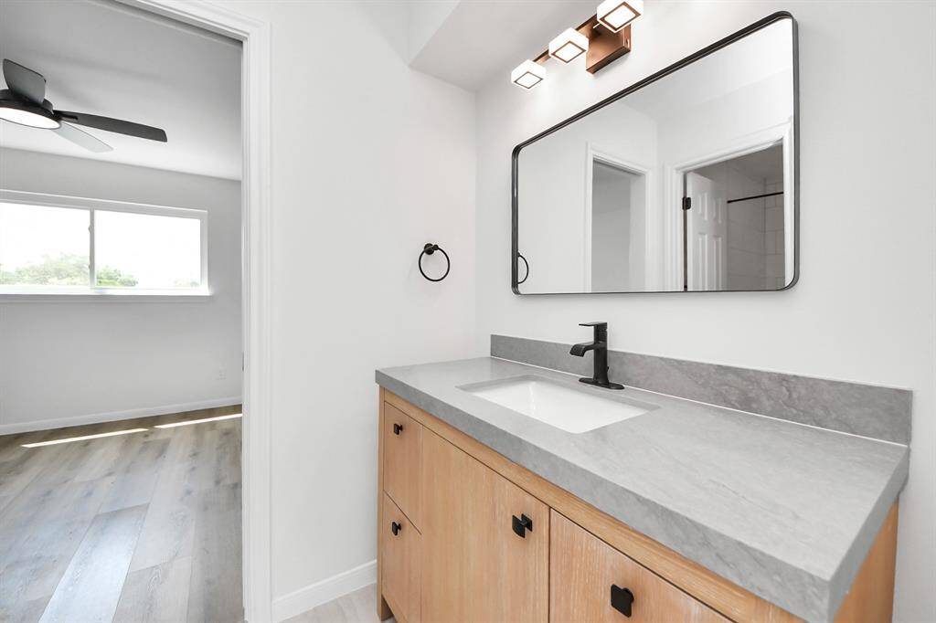 This updated secondary bathroom features a sleek vanity with quartz-style counters, matte black hardware, and contemporary lighting. Its clean, modern design perfectly complements the home's overall aesthetic.