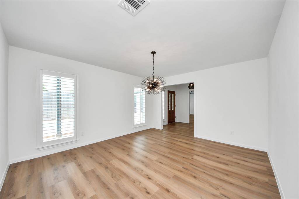 The formal dining room is bathed in natural light and features on-trend flooring and a striking modern chandelier—offering the perfect setting for elegant gatherings or intimate dinners.