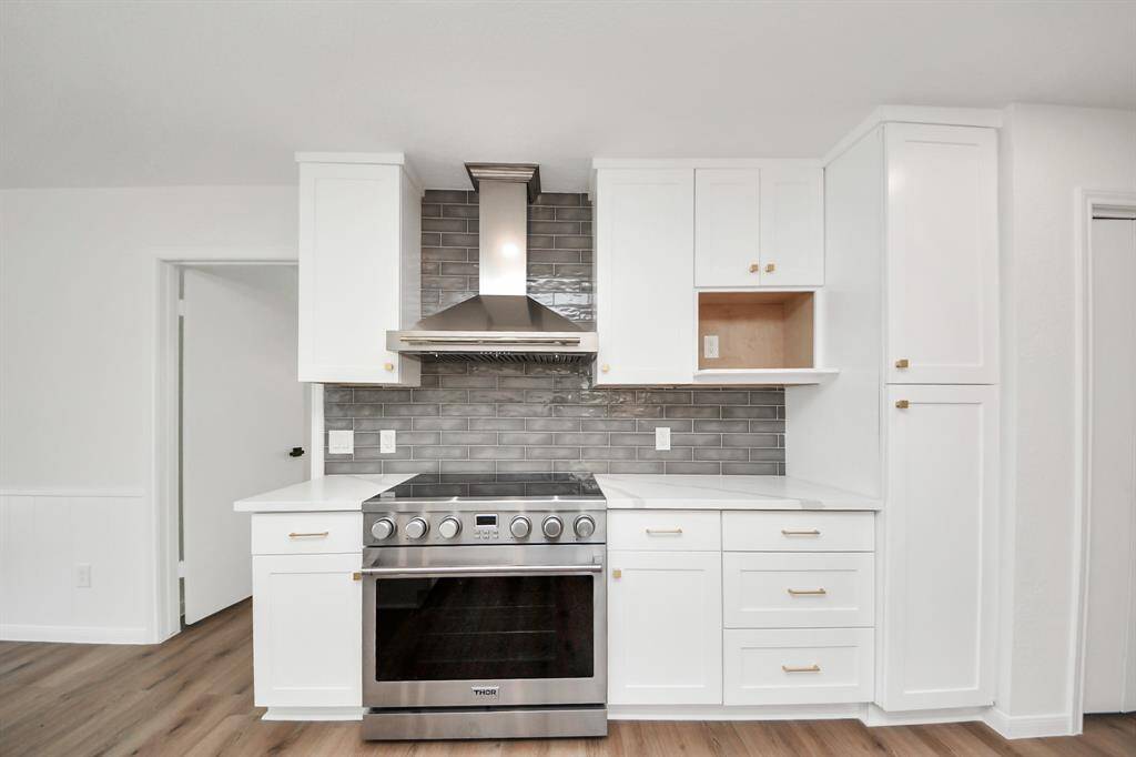 The kitchen showcases a sleek and modern design and a professional-grade Thor range with vent hood—ideal for both everyday cooking and gourmet entertaining.