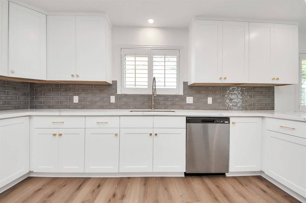 This light-filled kitchen offers a fresh, modern aesthetic with crisp white cabinetry, quartz countertops, and a designer subway tile backsplash.