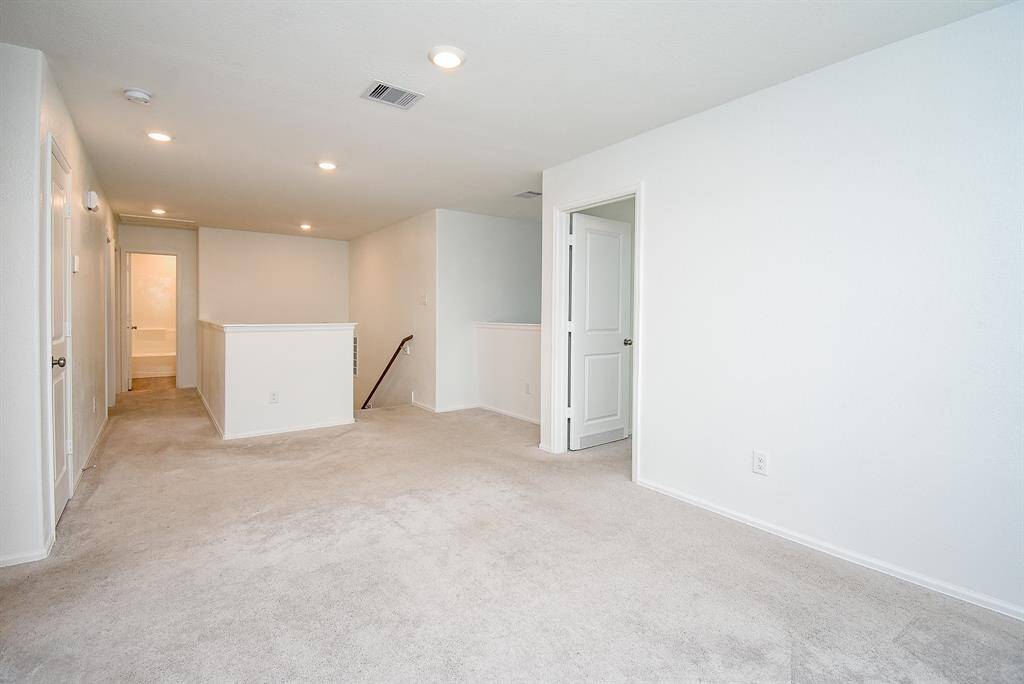 Spacious upstairs hallway with elegant recessed lighting, leading to bedrooms and bath.
