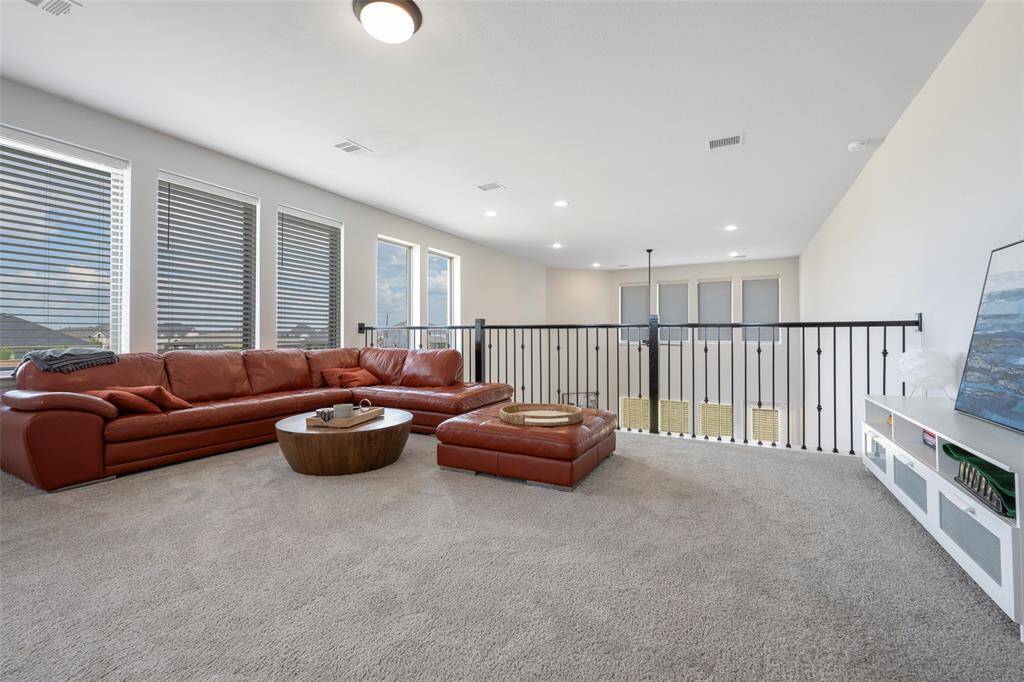 Spacious living area with large windows for natural light. Carpeted flooring complements the open, airy atmosphere ideal for relaxation or entertaining.