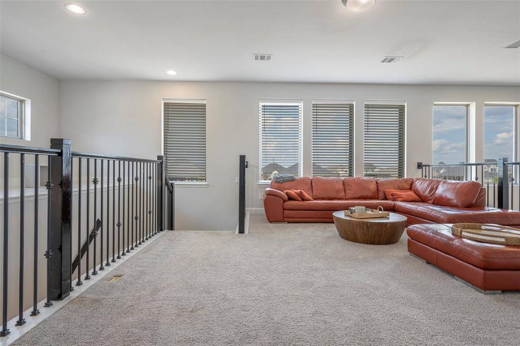 Bright and spacious loft, neutral carpeting, and multiple windows with blinds for natural light. Ideal for relaxation or entertaining.