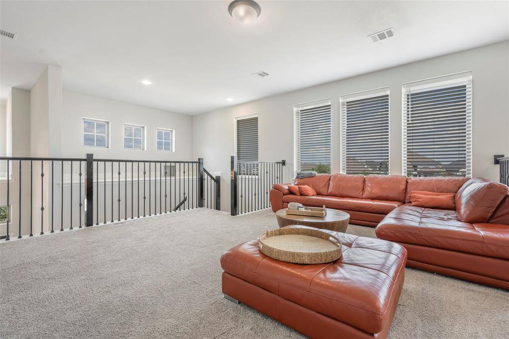 Bright and spacious loft with large windows, carpeted flooring, and a modern railing.