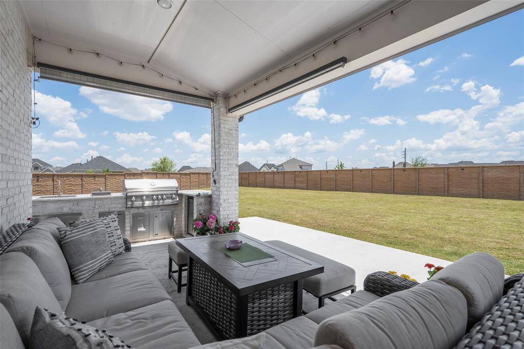 This photo showcases a spacious covered patio with a built-in grill, overlooking a large, fenced backyard. Ideal for outdoor entertaining and relaxation.