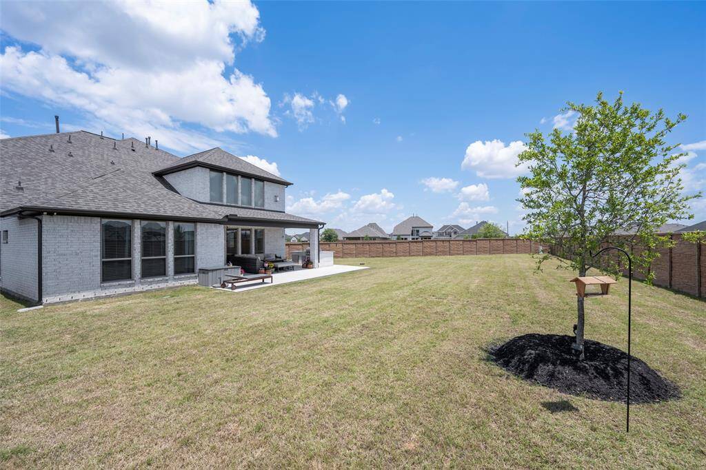 This photo showcases a spacious backyard with a well-maintained lawn. The area is enclosed by a wooden fence, providing privacy.