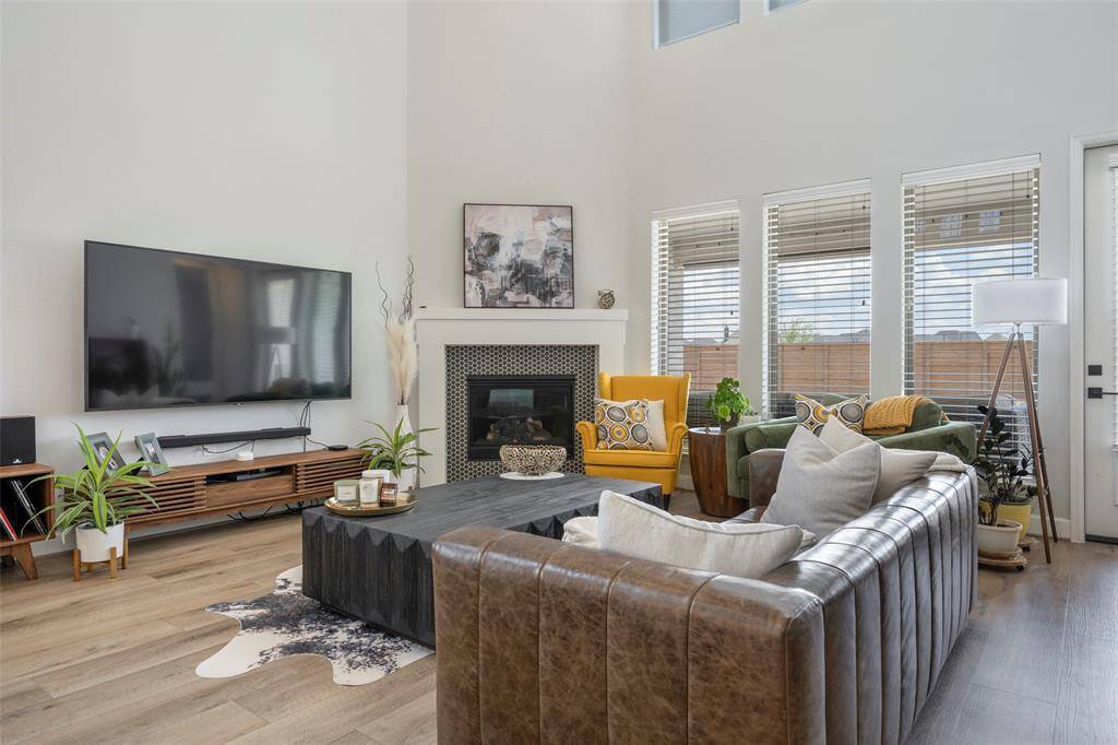 This spacious living room features a high ceiling, large windows for natural light, a cozy fireplace. Perfect for relaxation and entertainment.