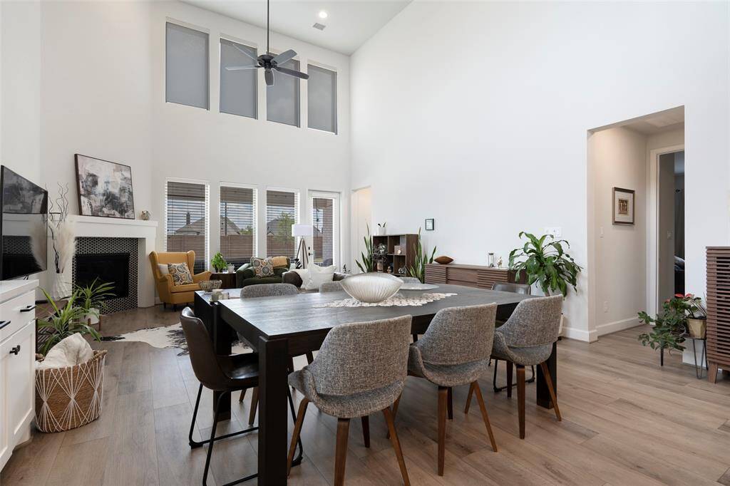 This spacious living area features high ceilings and large windows that fill the room with natural light. It includes a cozy fireplace, offering a perfect blend of comfort and elegance.