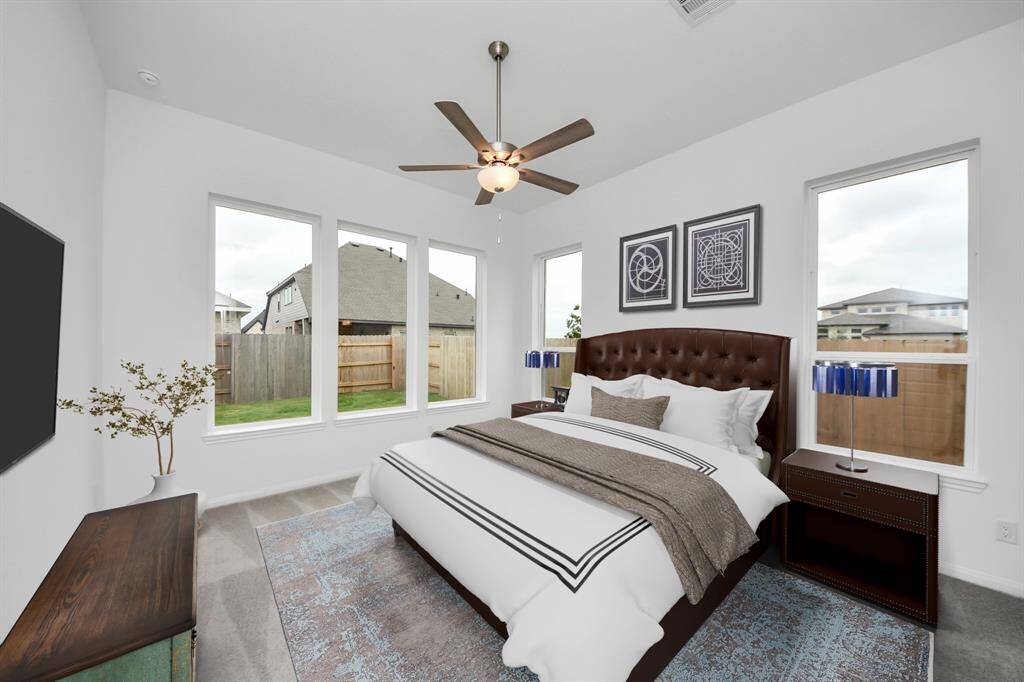 VIRTUAL IMAGE!This bright and inviting bedroom features large windows with backyard views, a modern ceiling fan, and elegant decor. Enjoy a comfortable bed with a tufted headboard, stylish bedside tables with lamps, and a wall-mounted TV.