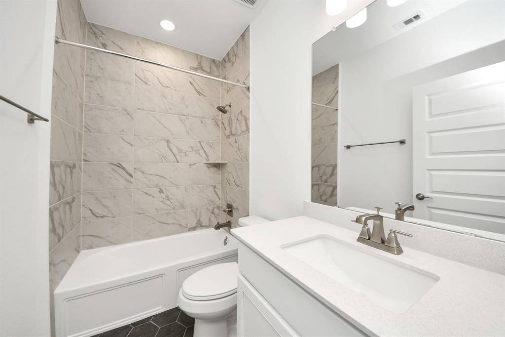 Elevate your daily routine in this modern bathroom featuring a luxurious marble-tiled shower and tub combo, a sleek white vanity with quartz countertops, and contemporary fixtures. Bright, fresh, and impeccably designed.