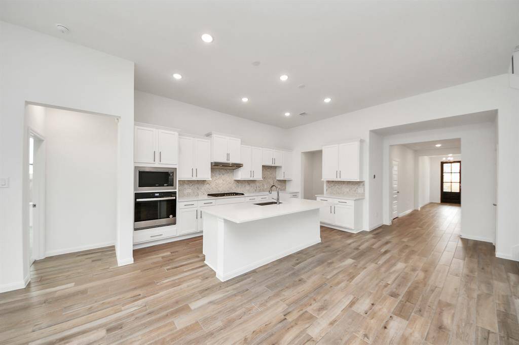 Experience a bright, spacious living area with large windows, hardwood floors, and a ceiling fan. The open layout and carpeted staircase enhance the modern, naturally lit ambiance.