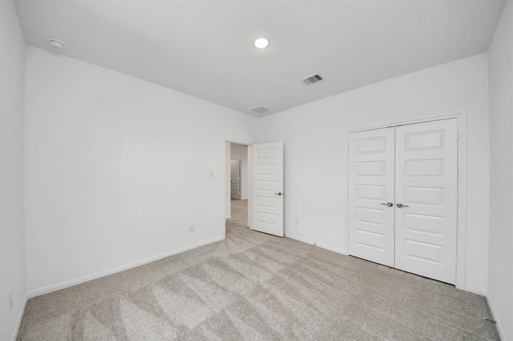 Discover a bright, spacious room with neutral carpeting, recessed lighting, and a built-in shelving nook. Enjoy ample natural light from multiple windows and convenient access to an open staircase.