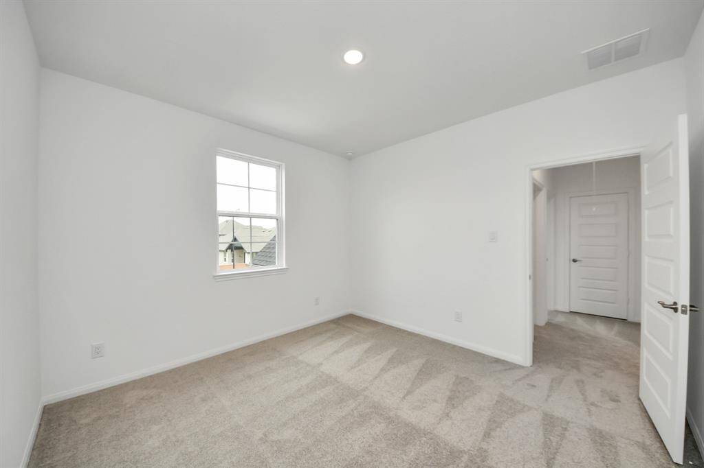 Bright and spacious room with clean white walls and neutral carpet, featuring natural light from a window. Includes two doors, ideal for a bedroom or home office.