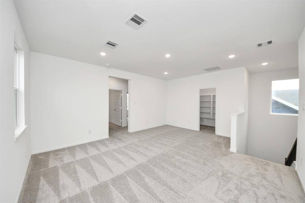 A bright, spacious bedroom with crisp white walls and plush carpet, featuring a closet and a sleek modern door for a fresh, minimalist appeal.