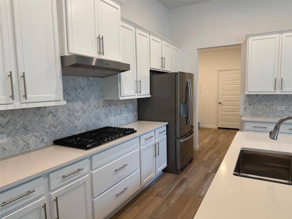 Bright and inviting laundry room featuring a front-loading washer and dryer, a window with blinds, and a convenient storage shelf. Enjoy the elegance of light wood flooring and crisp white walls.
