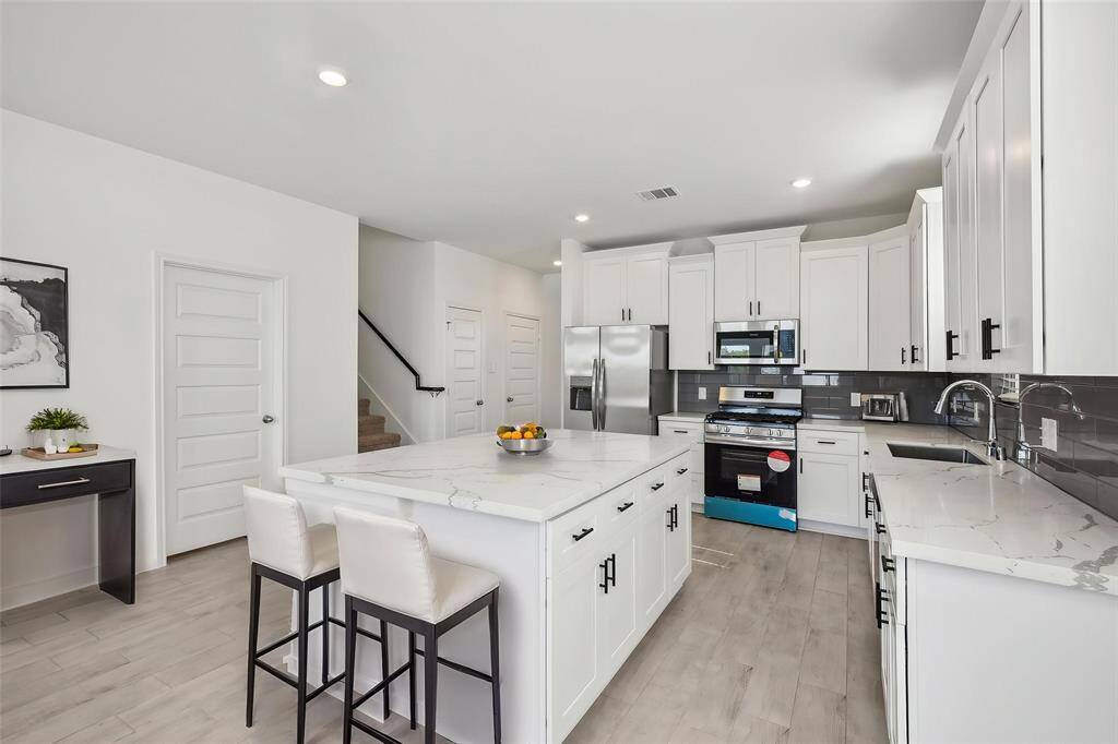 Notice the sleek, white cabinetry offering ample storage, complemented by the elegant countertops and contemporary hardware.