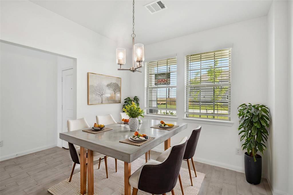 Picture the modern chandelier casting a warm glow over the dining table, creating a perfect ambiance for meals and conversations.