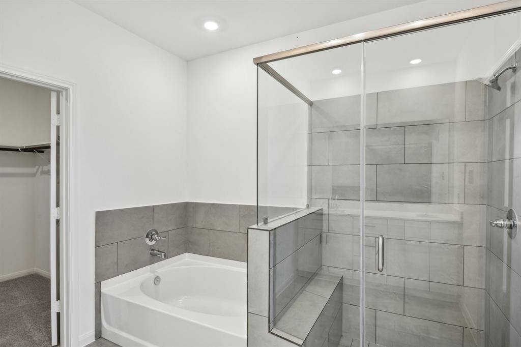 Indulge in this spa-like luxury within this beautifully designed bathroom and gorgeous soaking tub. The seamless glass enclosure defines the seperate shower with a built-in bench for added comfort.