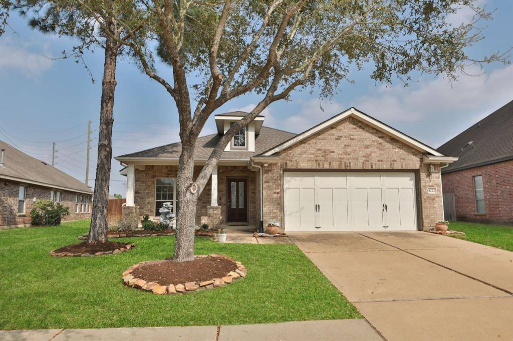 This is a beautiful single-story brick home featuring a two-car garage and a welcoming front porch. The well-maintained lawn and mature trees enhance its curb appeal, creating a cozy and inviting exterior.