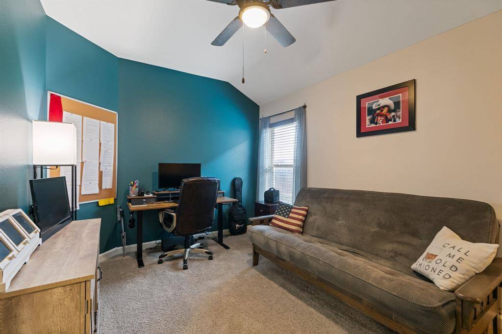 Experience comfort in this spacious bedroom, featuring a stylish accent wall, plush carpeting, and a ceiling fan.