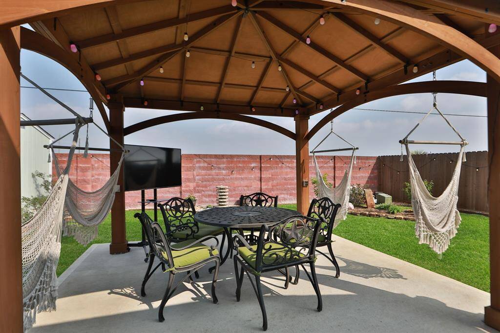 This backyard features a charming gazebo that creates a perfect outdoor relaxation and entertainment space. The area is complemented by lush green grass and a privacy fence.