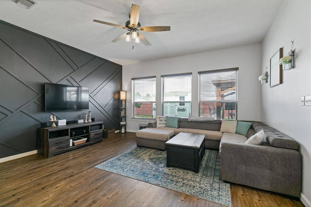 The family room features laminate wood floors, a stunning accent wall, and expansive windows with backyard views.
