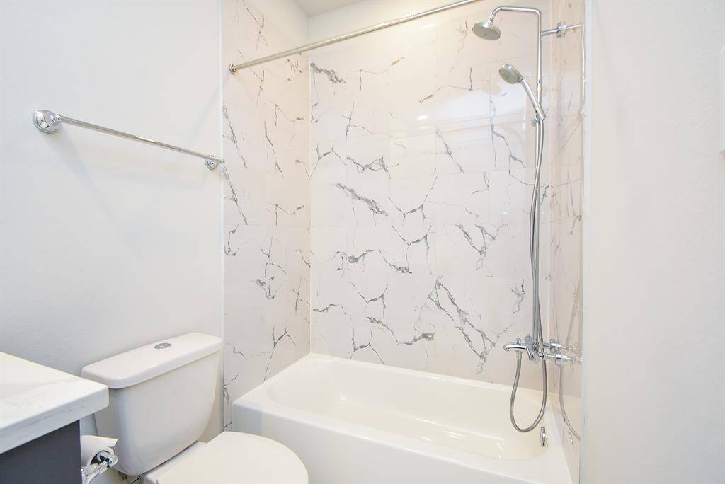 The bathroom has a gorgeous shower/tub combo and tile walls.