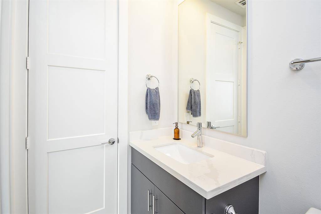 The bathroom includes quartz countertops, wooden cabinetry, and a built-in closet.