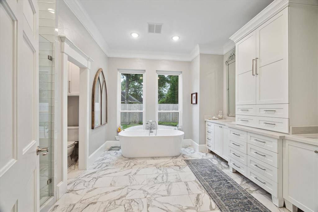 Renovated PRIMARY BATH is a luxurious retreat with the finest finishes offering a soaking tub, decorative mirrors over each vanity and seamless glass shower.