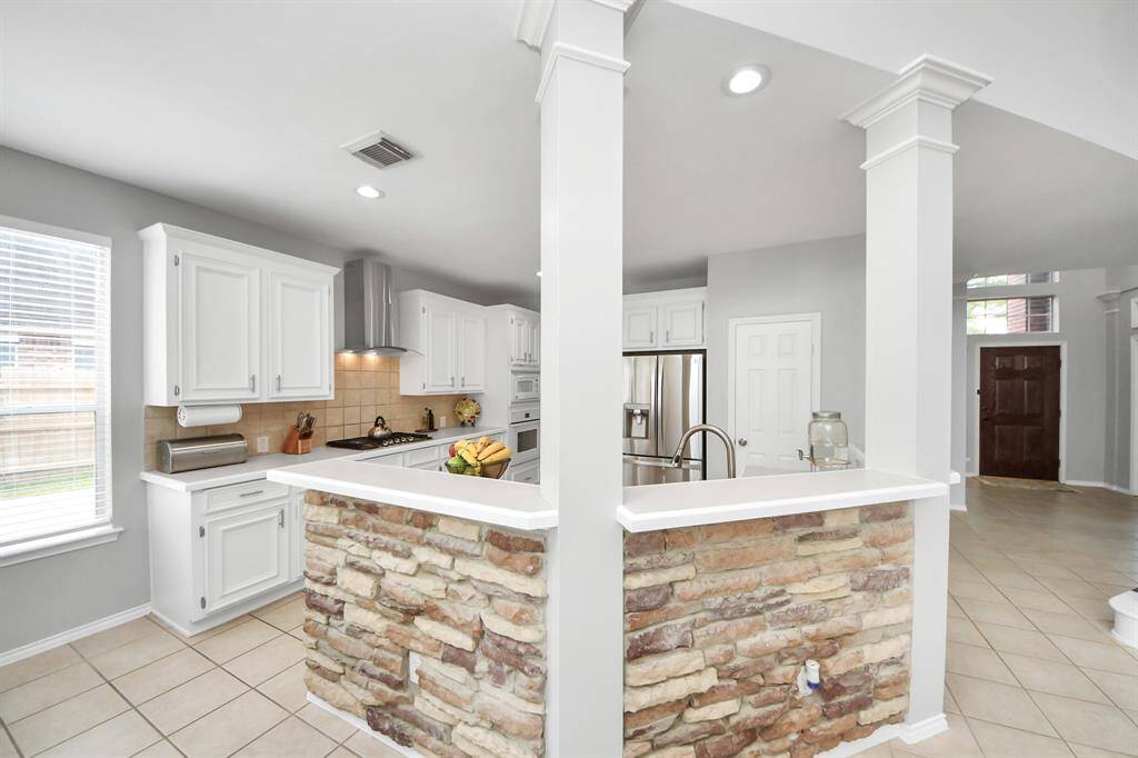As you approach the kitchen, take note of the expansive breakfast bar that overlooks the space, creating a seamless flow between the kitchen and family room. The beautiful stacked stone accents add a touch of rustic elegance.