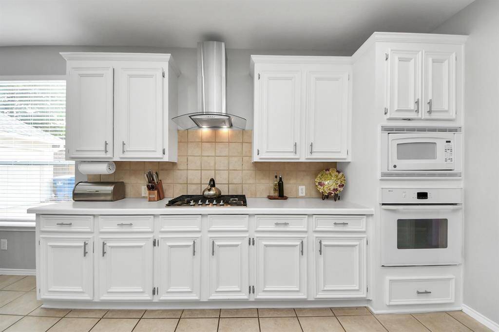 This kitchen combines both form and function, creating an inviting space for cooking and entertaining. The built-in oven and microwave provide streamlined convenience, allowing for easy meal preparation, while the gas cooktop with a venthood ensures optimal cooking performance and efficient ventilation.