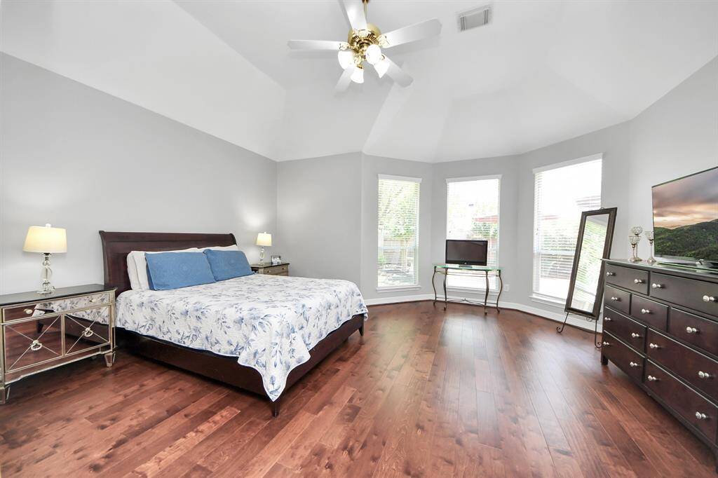 The first-floor primary retreat is a serene and spacious sanctuary, featuring vaulted ceilings with a ceiling fan that enhance the sense of openness and comfort.  A large bay window creates a cozy sitting area, allowing natural light to flood the space and offering the perfect spot to unwind with a book or enjoy the view.