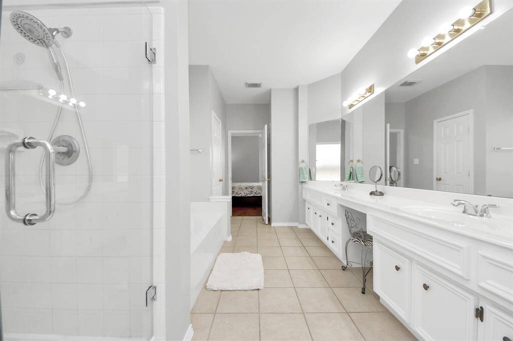 The bathroom also boasts a large garden tub, a serene spot to unwind after a long day, and a separate frameless glass walk-in shower, offering both luxury and convenience.
