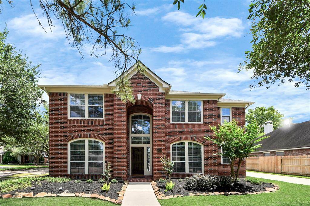 The classic brick elevation, complemented by mature trees, lush green grass, and large stone-lined flower beds, creates a striking first impression that welcomes you home.