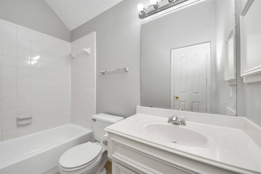 This full secondary bathroom features a white vanity with a frameless mirror and overhead vanity lighting. The tub/shower combo offers versatile options for both baths and showers.
