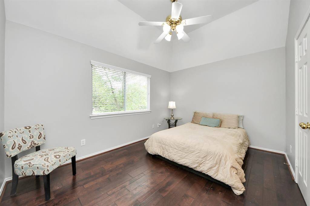 This oversized secondary bedroom boasts a soaring vaulted ceiling, creating an open and airy feel. A large window allows natural light to flood the space, highlighting the gleaming wood floors. The room also features a double-door closet, providing ample storage space for all your needs.