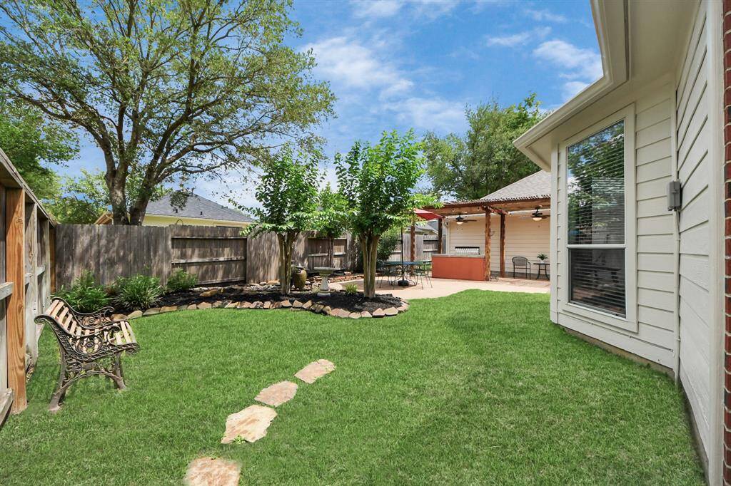 The backyard is a true oasis, featuring lush green grass and stone-lined flower beds that add a touch of natural elegance. Tranquil waterfall features enhance the space, creating a serene atmosphere with their soothing sounds—perfect for moments of self-reflection or peaceful relaxation.