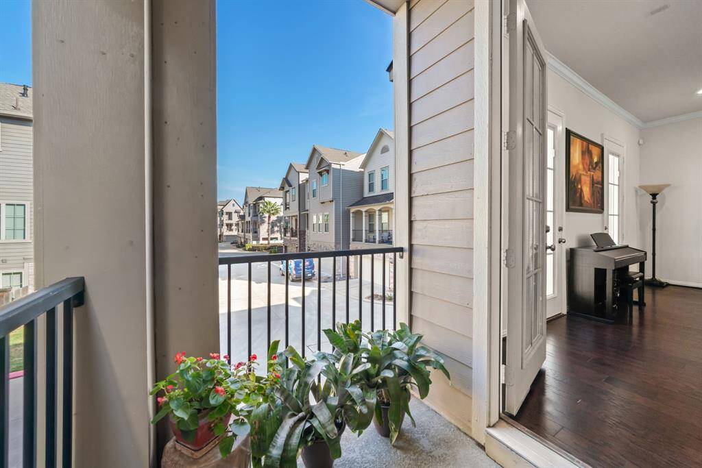 This inviting entryway features a carpeted staircase with elegant wrought iron railings, complemented by natural light streaming through a large window. The space is accented with wood flooring and tasteful decor.