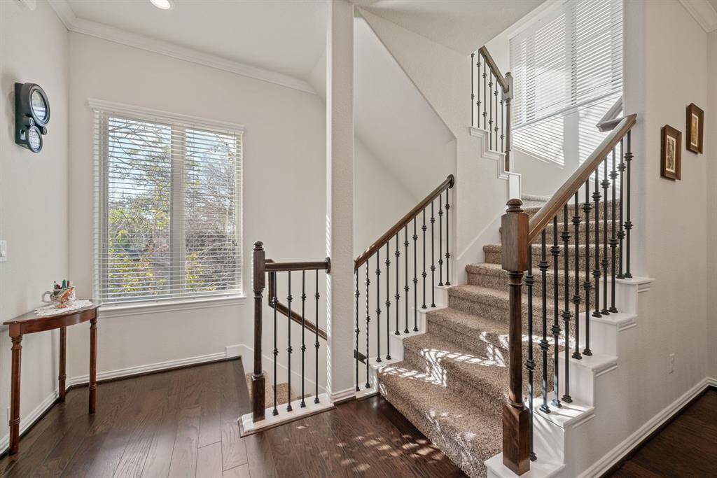 This bedroom features hardwood floors, a ceiling fan, and ample natural light from multiple windows. It includes a cozy bed area, wooden furniture, and direct access to an en-suite bathroom, providing comfort and convenience.