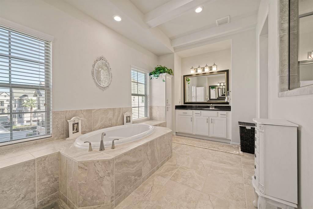 This photo shows a modern bathroom with a glass-enclosed shower featuring elegant tile work. Adjacent is a spacious walk-in closet with ample clothing storage.