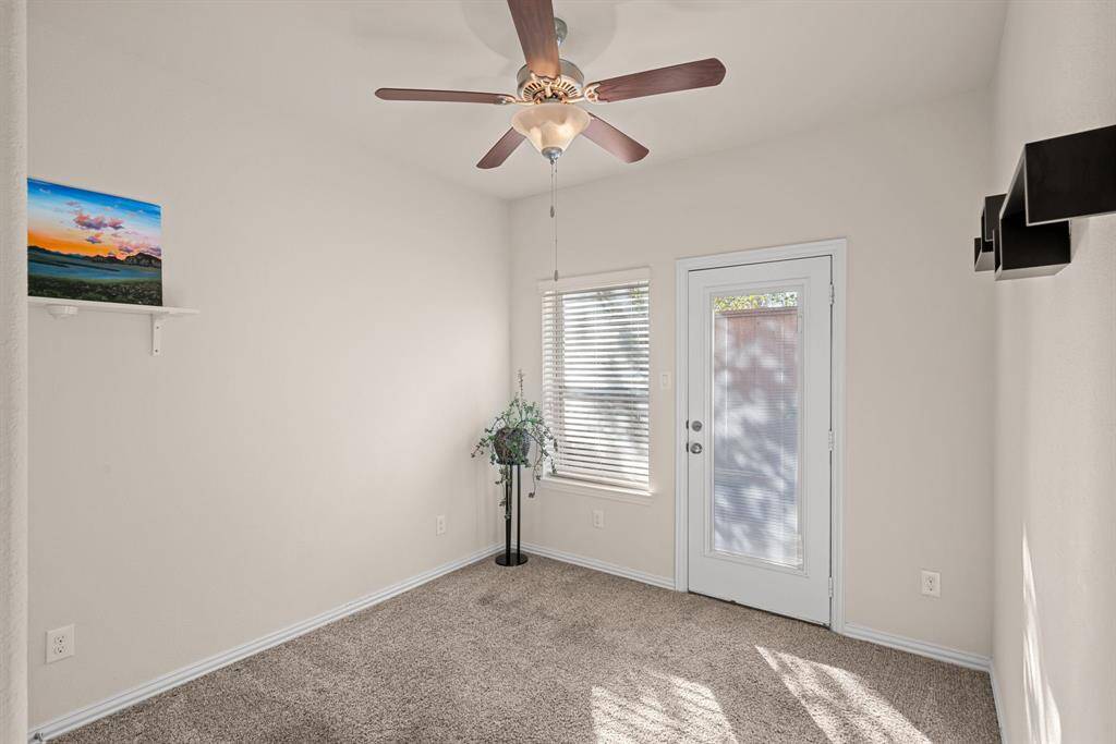 This bright room features soft carpet flooring, a ceiling fan, and a double-door closet. Decorative shelves and neutral walls offer a versatile space, ideal for a bedroom or home office.