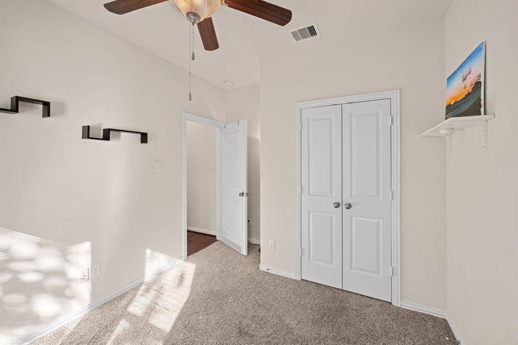 This bathroom features a modern design with a bathtub and shower combo, beige tile surround, and a white vanity with a black countertop. A large framed mirror and overhead lighting complete the clean, stylish look.