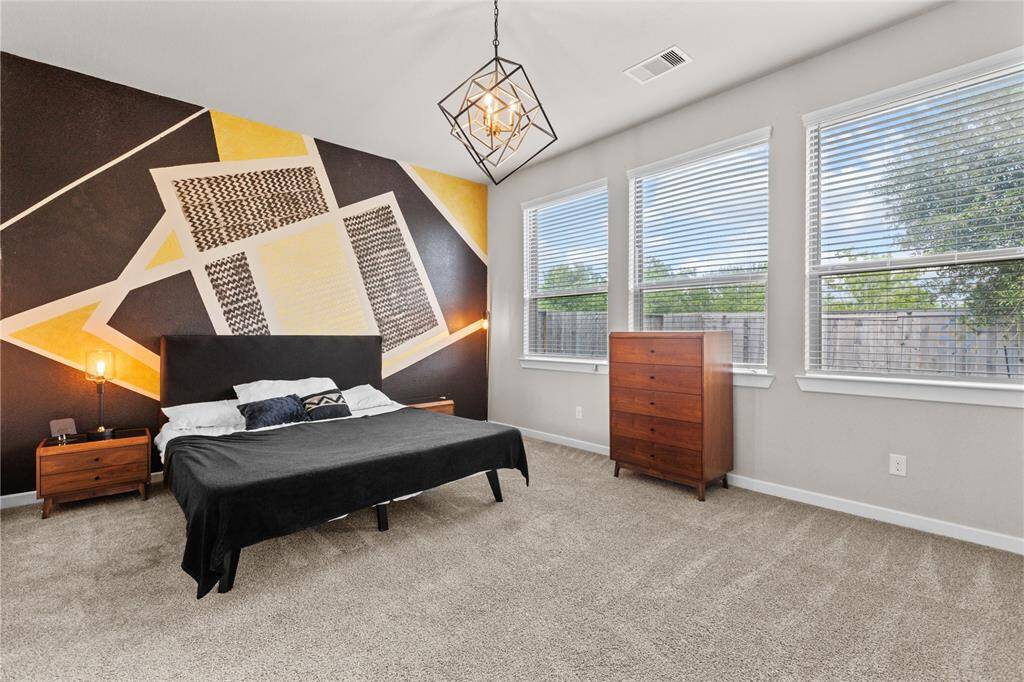 Spacious primary bedroom with stylish accent wall and room for additional seating.